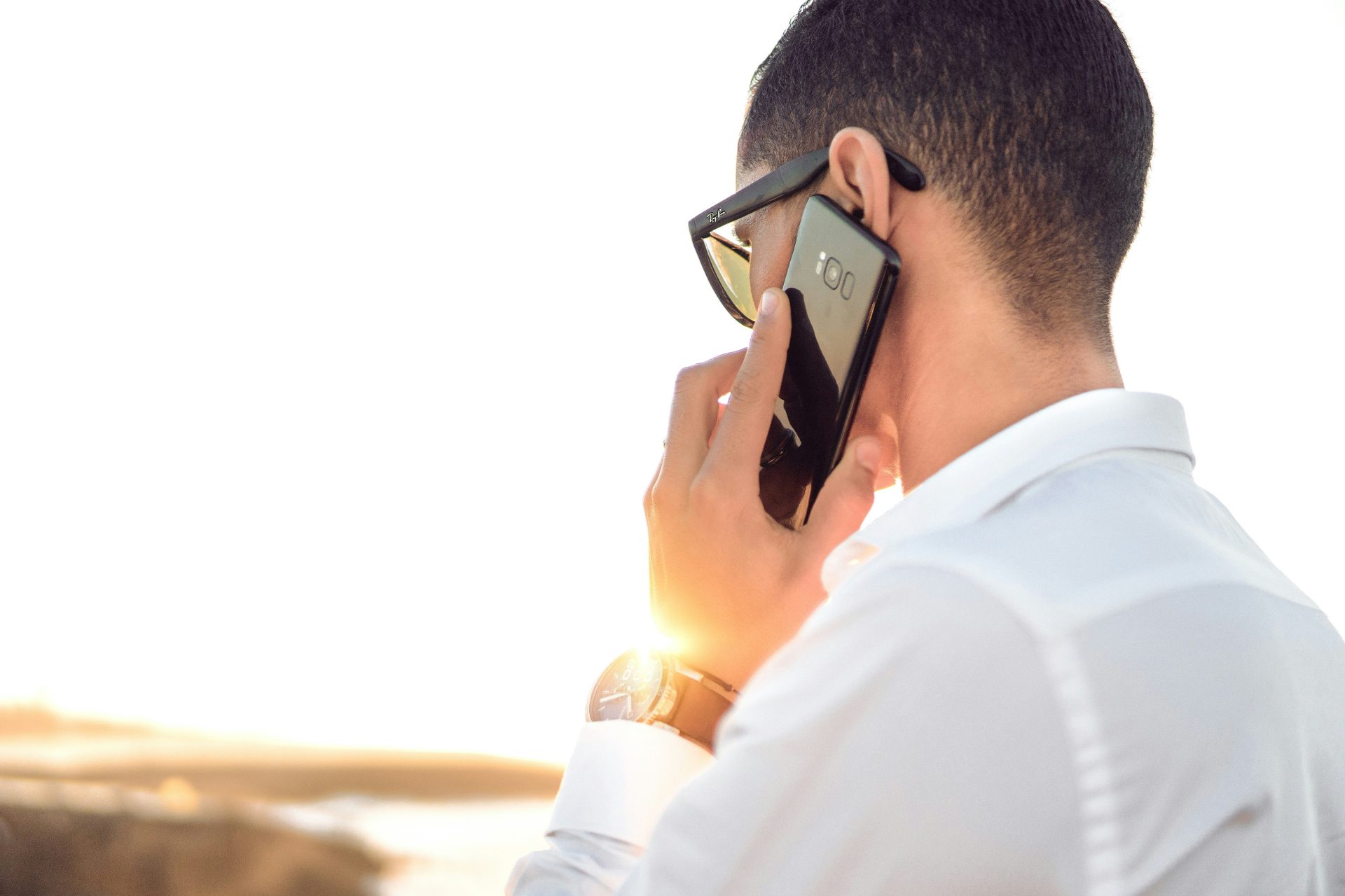 hombre sosteniendo un teléfono inteligente de pie frente a una masa de agua tranquila
